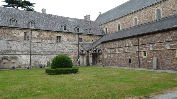 La Lucerne abbey cloister, stone walls, green lawn and overcast sky