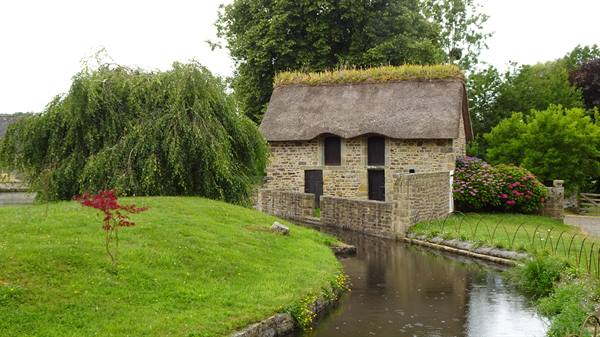 Saint-Céneri-le-Gérei, old stone building with thatched roof beside the river
