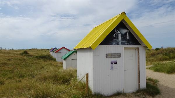 Colorful beach cabins lined up on the grassy dunes of Gouville sur Mer