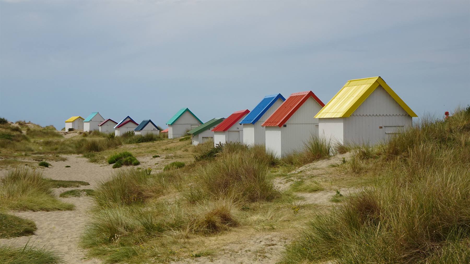 Cabine bianche dai tetti colorati tra le dune erbose di Gouville sur Mere