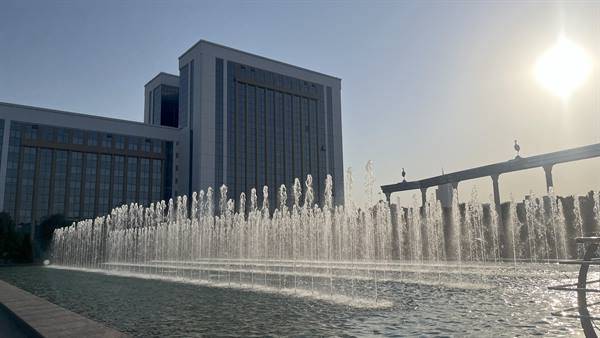 Fontane in acqua contro il palazzo governativo a Tashkent, a sole alto