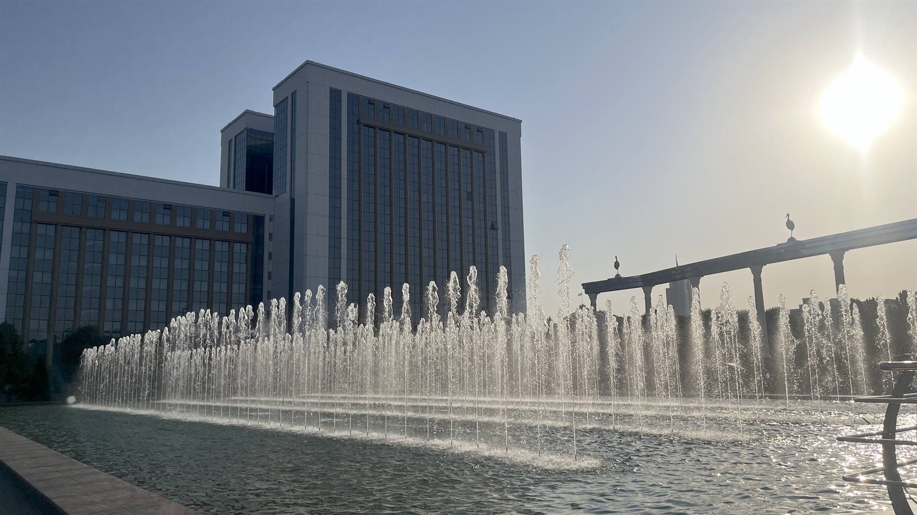Fontane in acqua contro il palazzo governativo a Tashkent, a sole alto