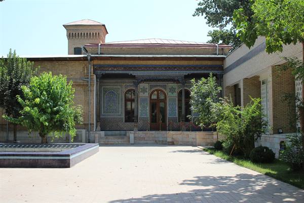 Palazzo in mattoni decorati con maioliche blu nel cortile ombreggiato di Tashkent