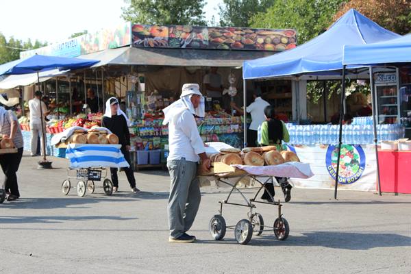 Il venditore spinge il carrello pieno di pane al mercato di Tashkent