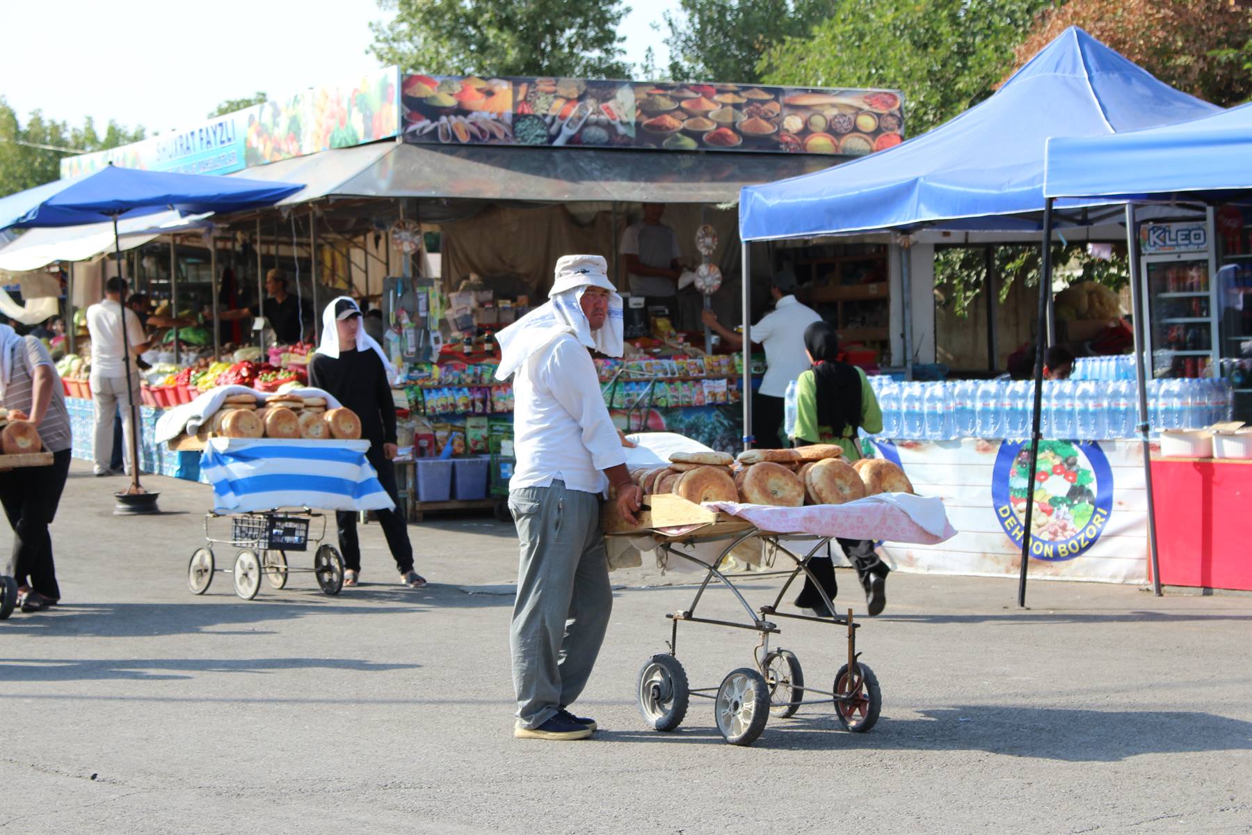 Il venditore spinge il carrello pieno di pane al mercato di Tashkent