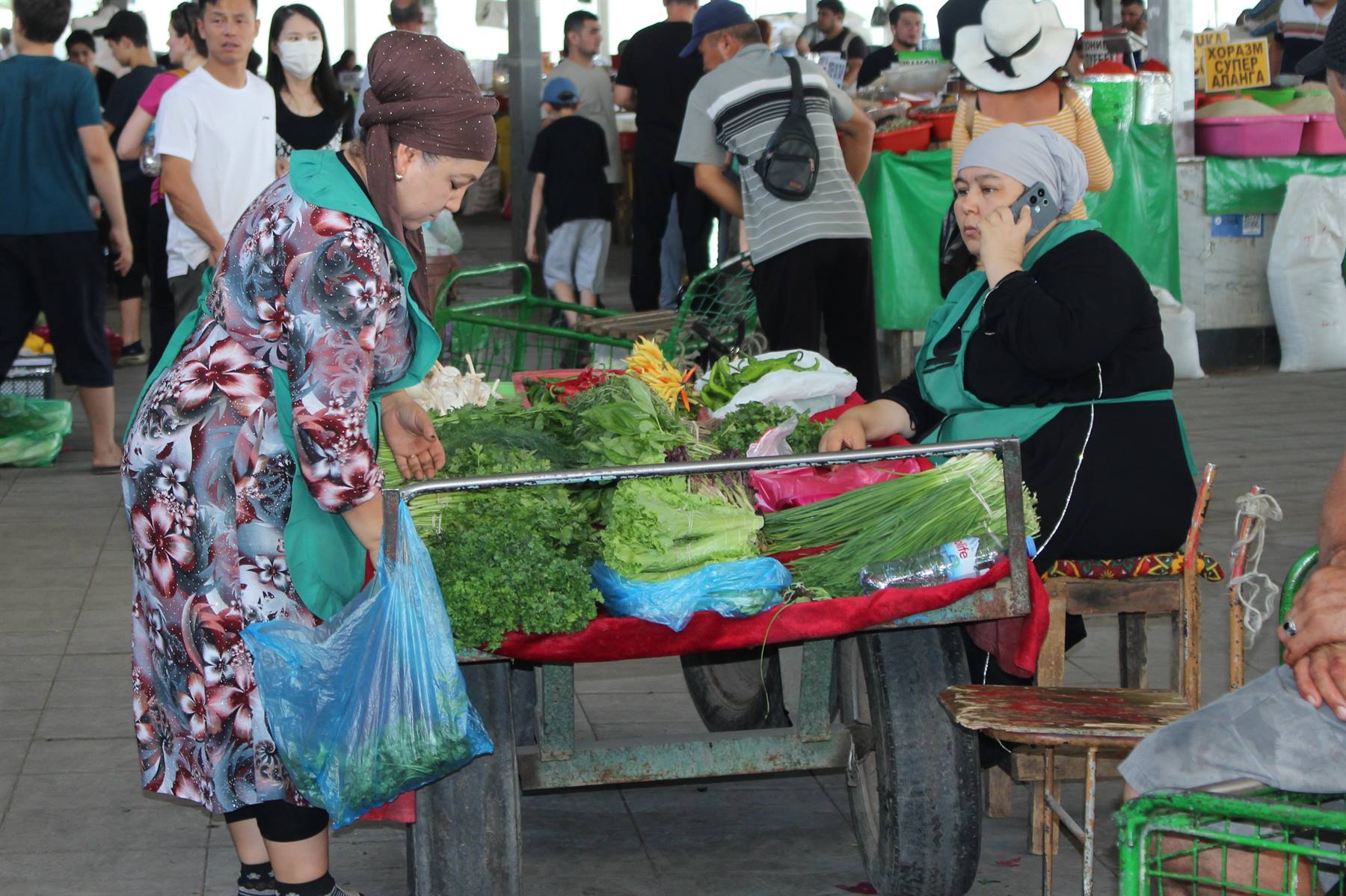 Mercato di Tashkent: donna compra verdure da vendtrice al telefono