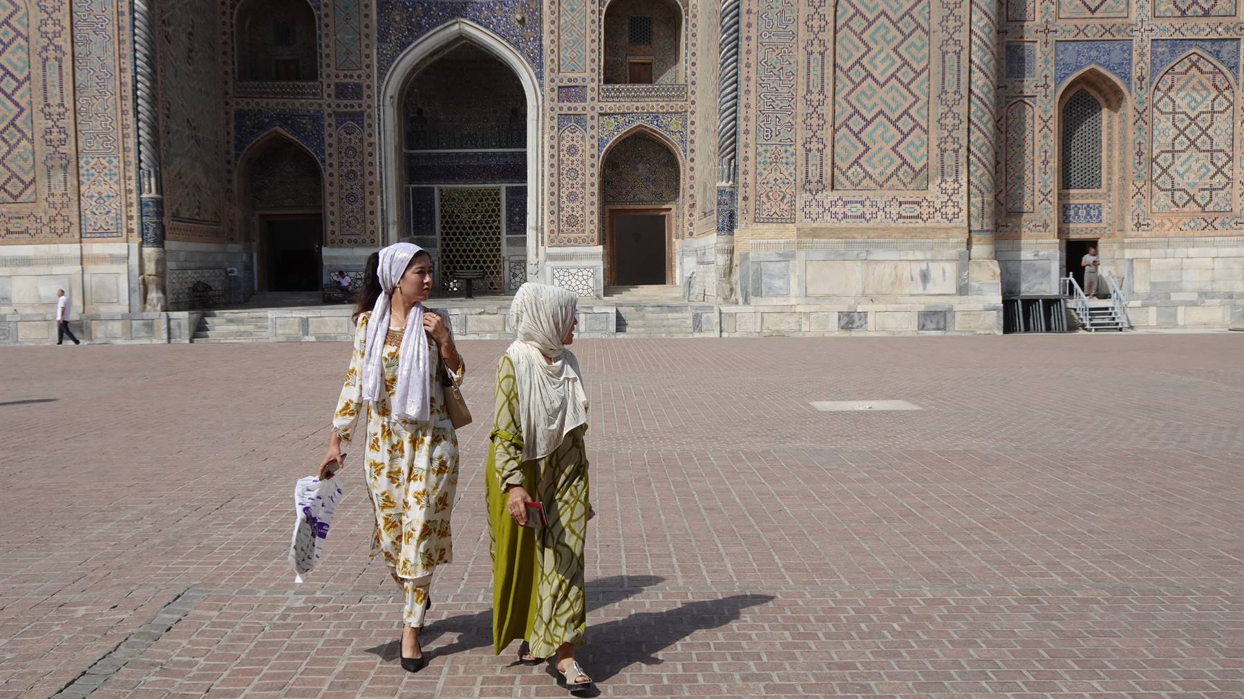 Due donne velate camminano sulla piazza del Registan a Samarcanda