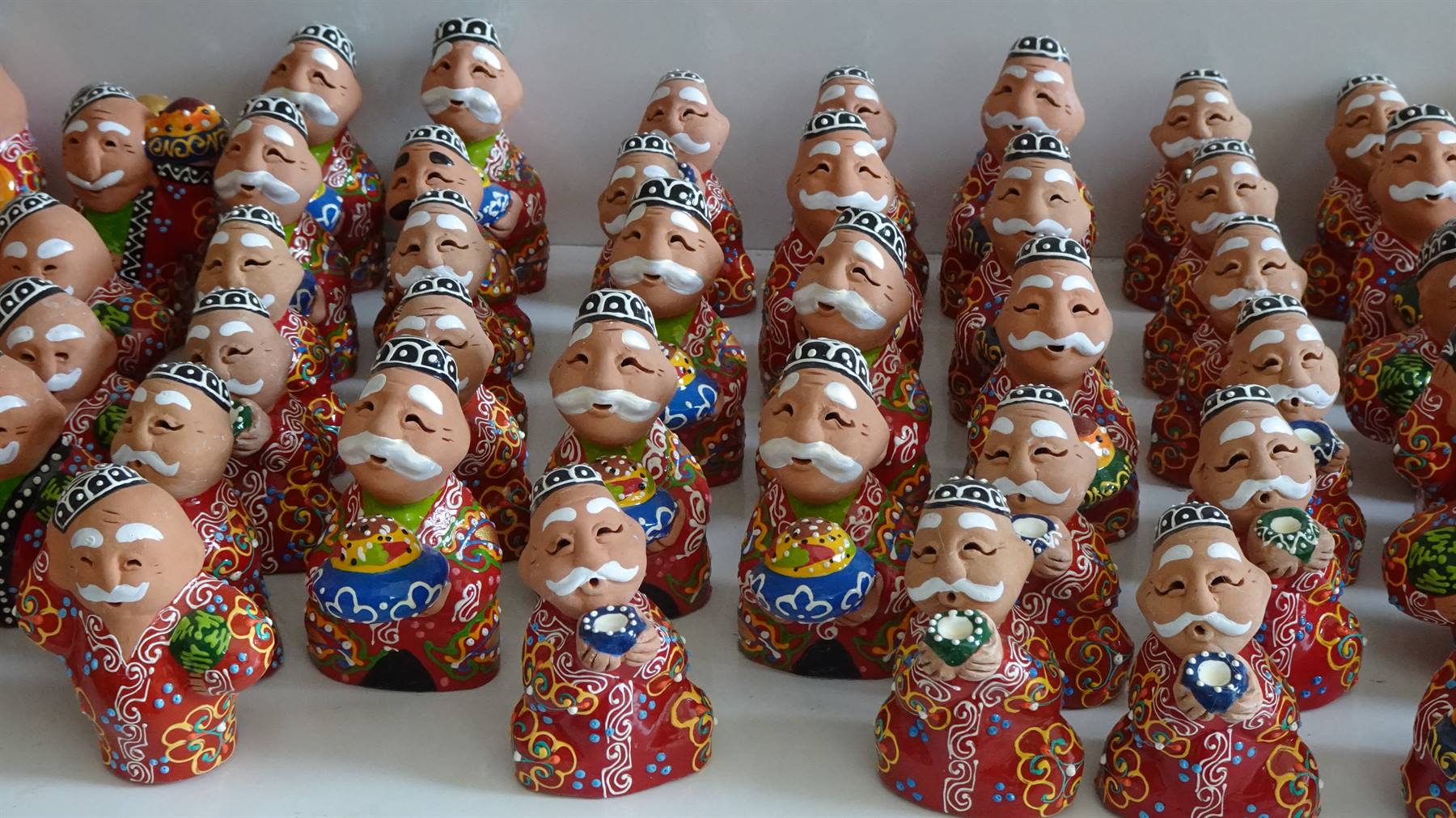 Statuette in ceramica dipinta di anziani sorridenti, mercatino di Samarcanda
