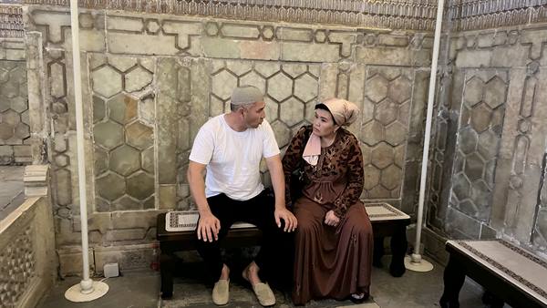 Pellegrini seduti tra le maioliche esagonali del mausoleo, Samarcanda
