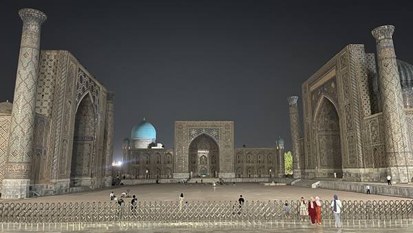 Piazza Registan di Samarcanda illuminata di notte tra madrase e minareti