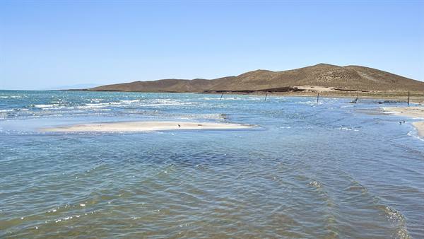 Acque basse e sabbia bianca sotto le colline aride del lago Aydar