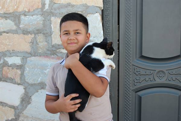 Ragazzo con gatto bianco e nero davanti a un portale, Samarcanda