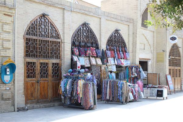Bazar sotto i portici in mattoni con archi a graticcio, stoffe e borse appese