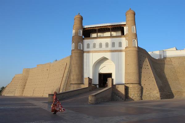 Turista in abito floreale cammina davanti all'Ark di Bukhara