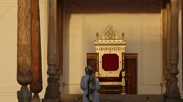 Donna davanti a un trono dorato intarsiato nel palazzo di Bukhara