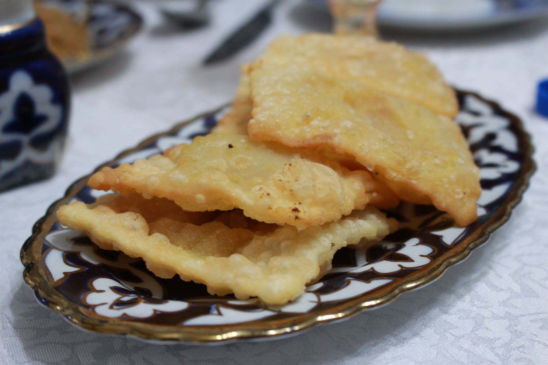 Frittelle dorate su piatto decorato in ceramica, tavola imbandita