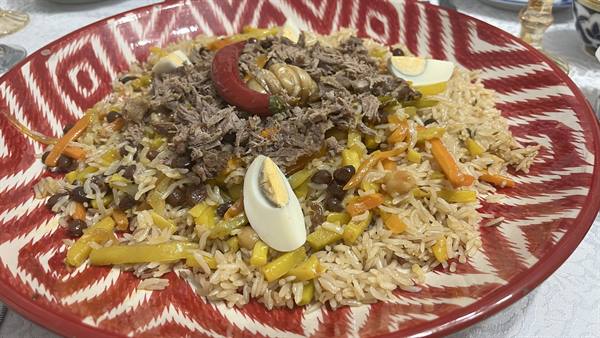 Plov con carne, uova e carote nel piatto rosso motivato di Samarcanda