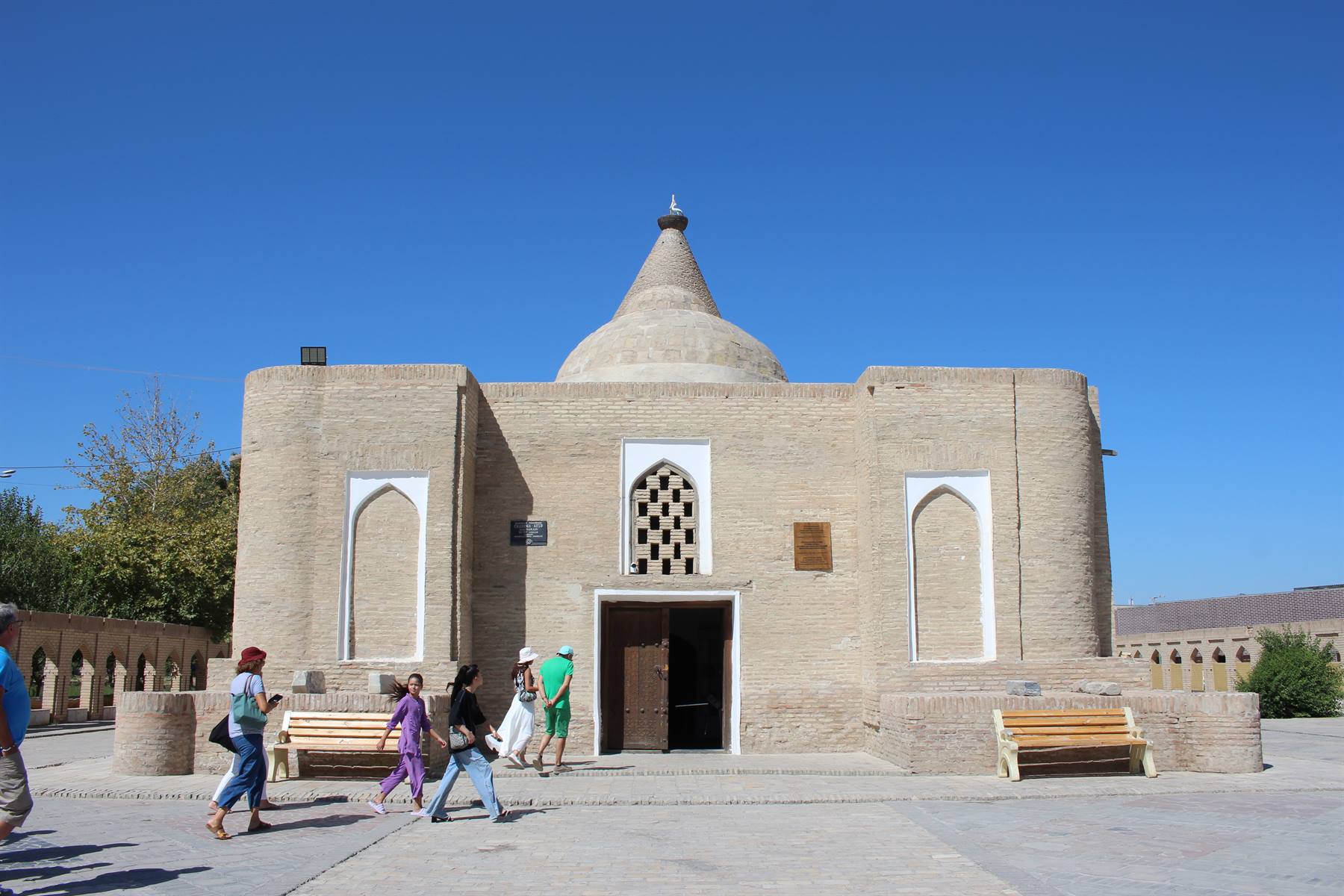 Turisti entrano nel mausoleo di mattoni con cupola conica a Bukhara