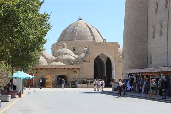 Turisti sotto le cupole in mattoni del bazar coperto di Bukhara