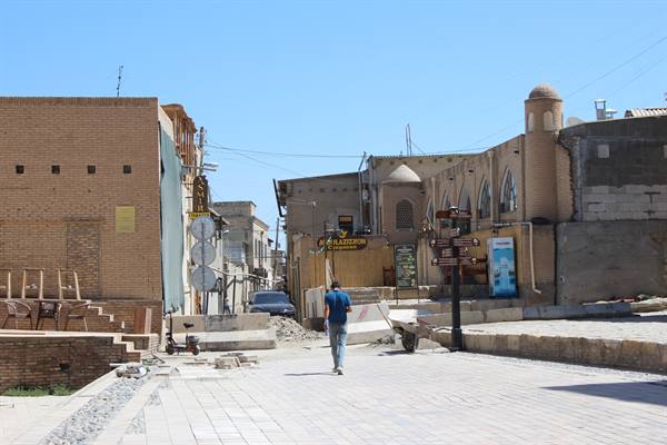 Turista cammina tra strade di mattoni e cupole sotto il sole di Bukhara