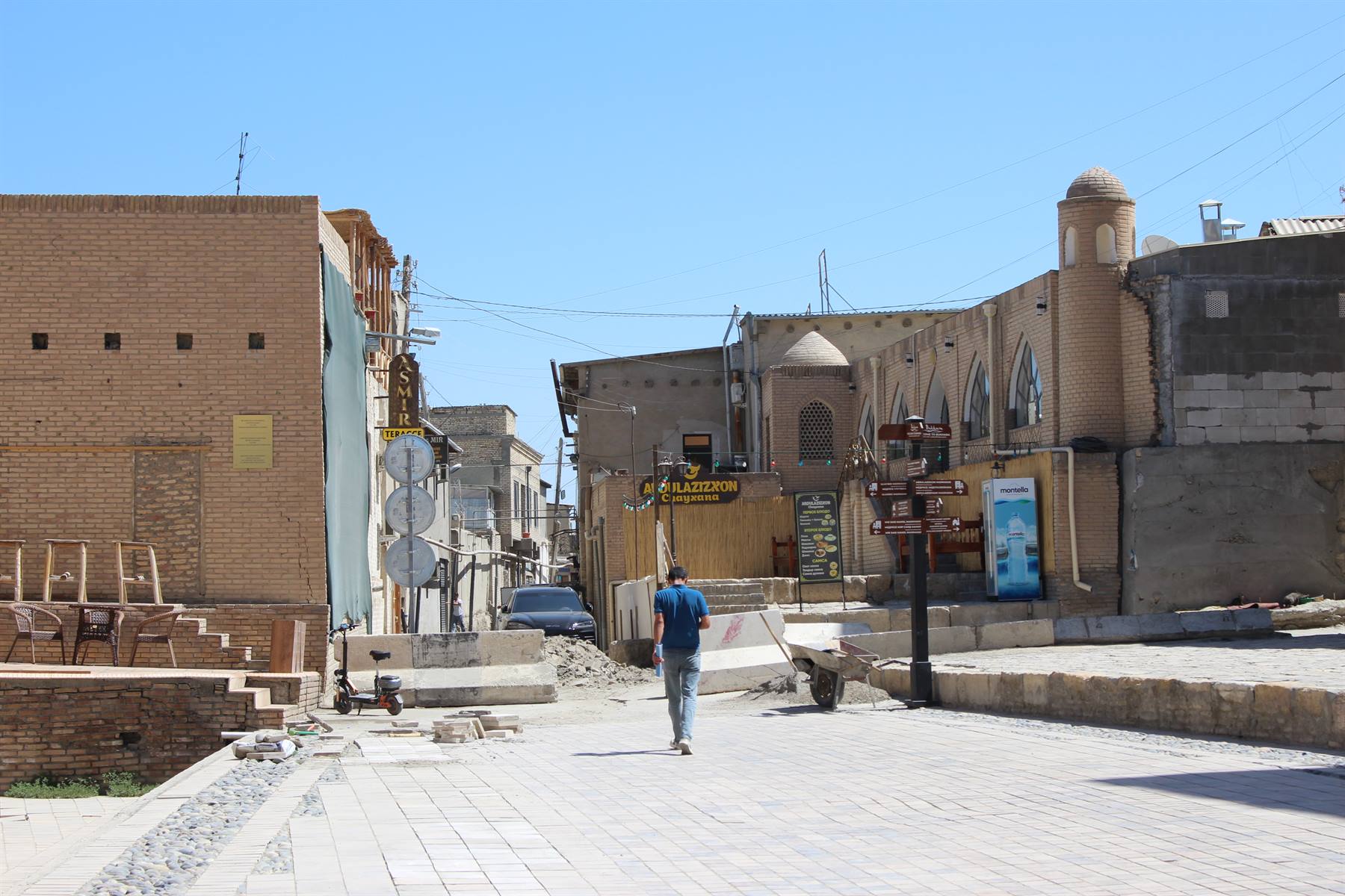 Turista cammina tra strade di mattoni e cupole sotto il sole di Bukhara
