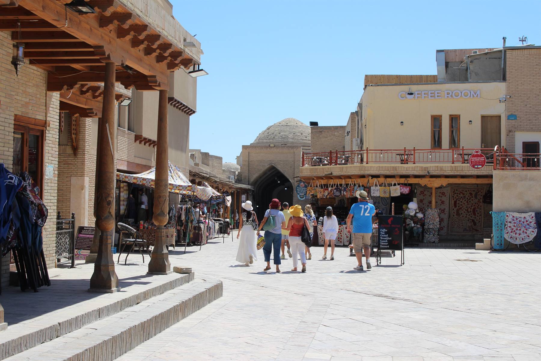Turisti camminano tra le bancarelle del bazar di Khiva, mattoni in sole