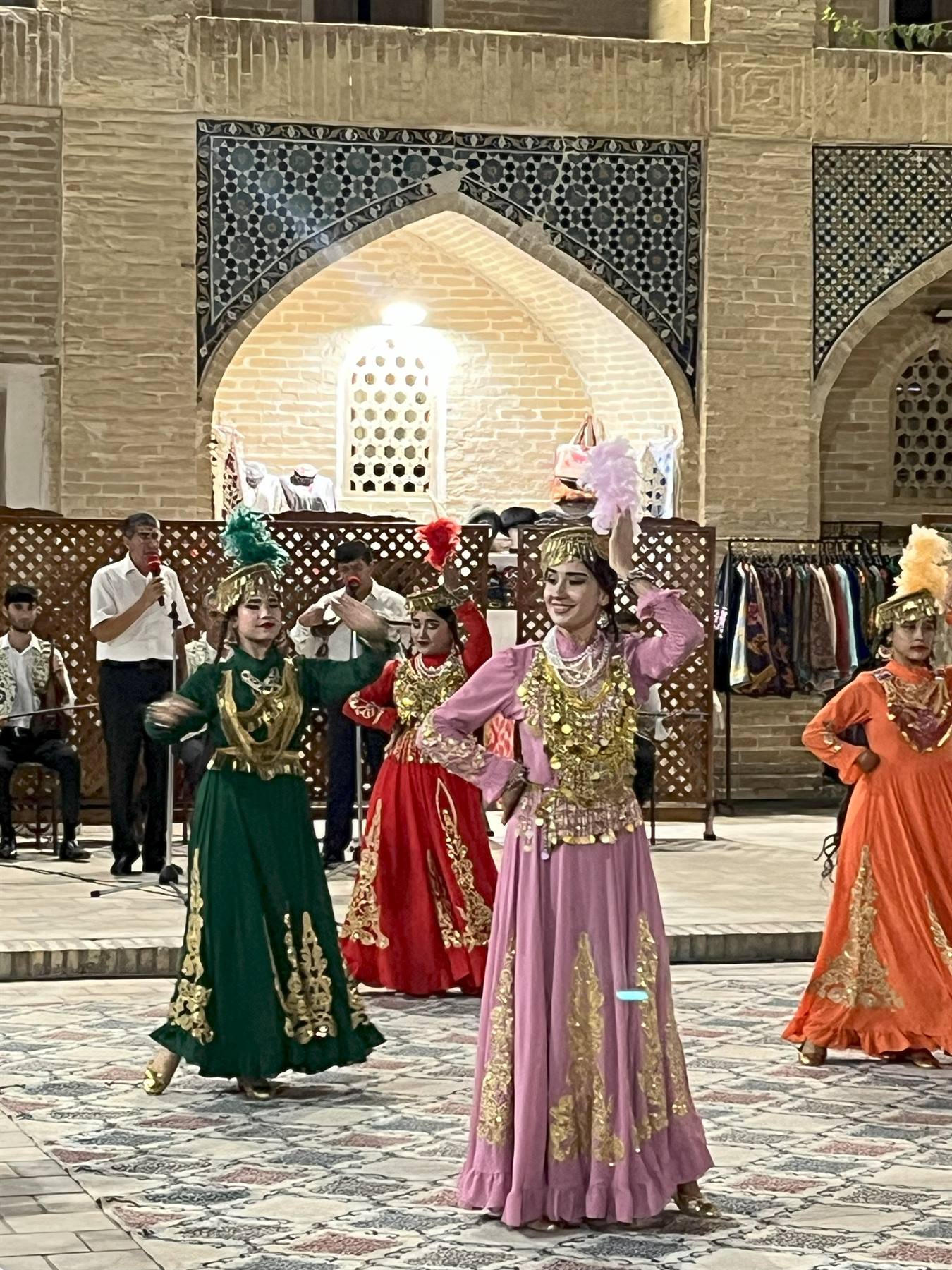 Ballerine in abiti colorati danzano nel cortile in mattoni di Bukhara