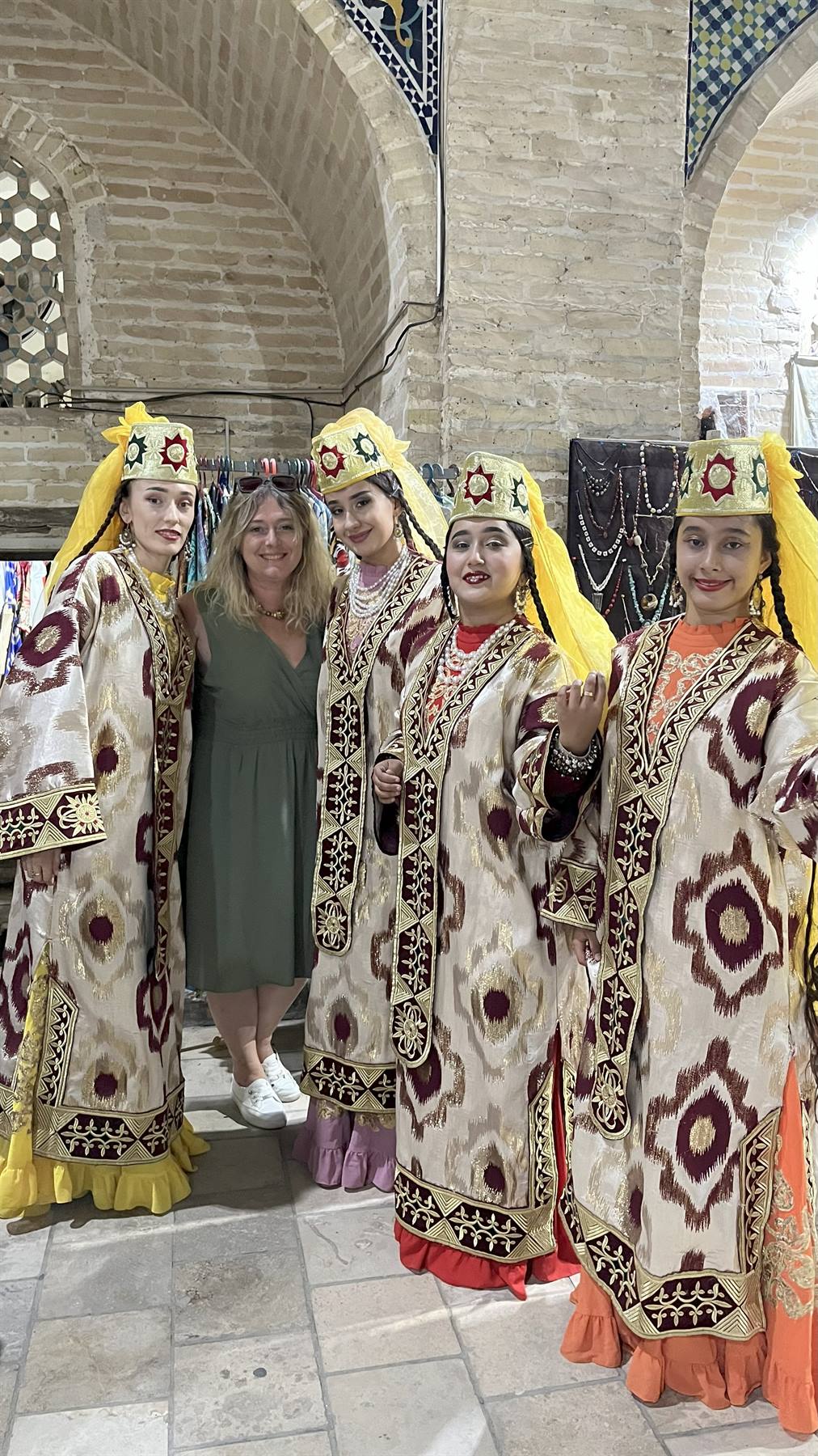 Turiste e ballerine in ikat dorato nel bazar coperto di Bukhara