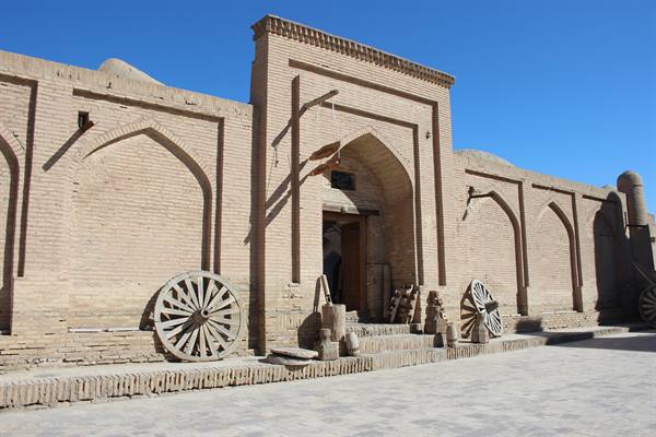 Vecchie ruote di legno contro il muro di mattoni dell'madrasa a Khiva