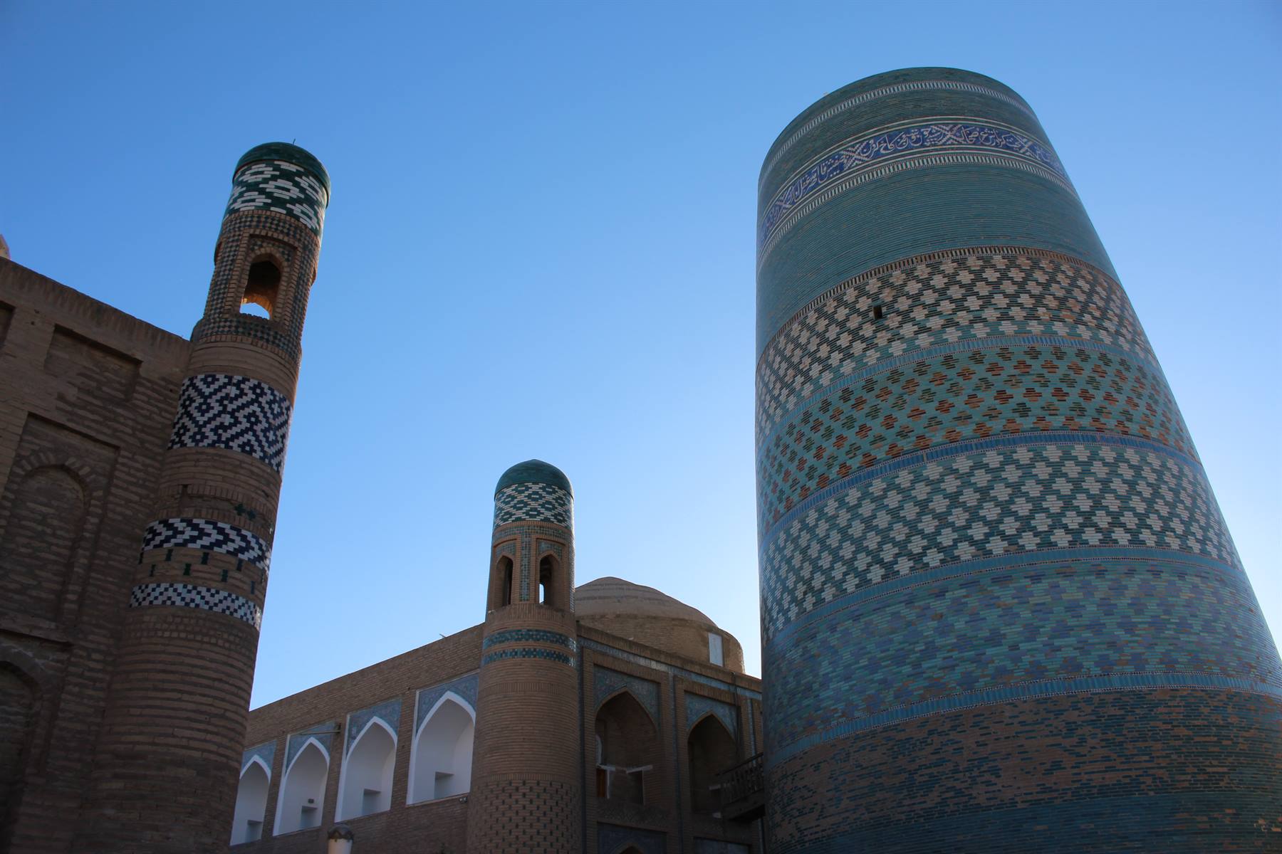 Minareti e madrasa con maioliche blu a Khiva, cielo terso