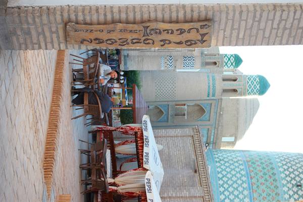 Tavoli di un caffè accanto ai minareti maiolicati di Khiva