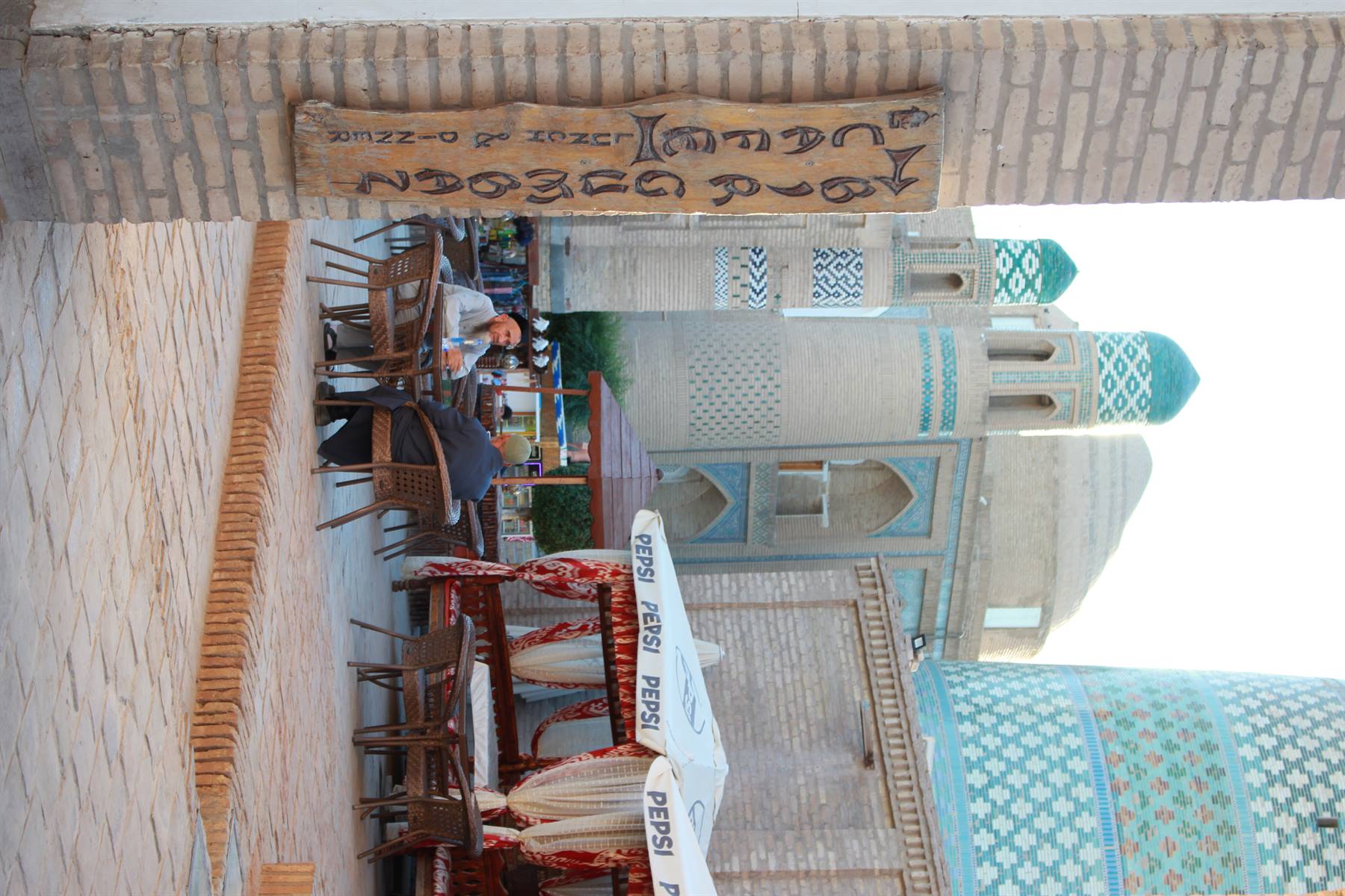 Tavoli di un caffè accanto ai minareti maiolicati di Khiva