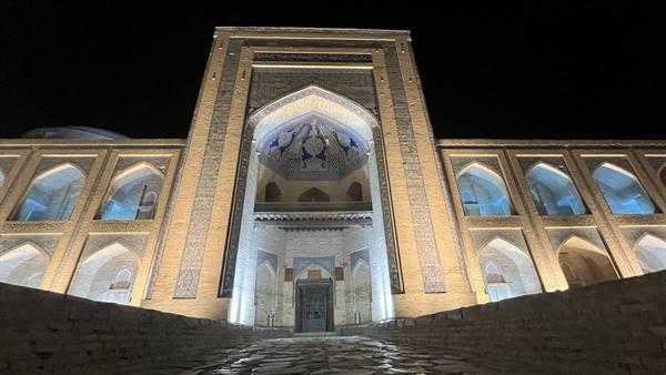 Madrasa in mattoni illuminata di notte, cupola maiolicata blu, Bukhara