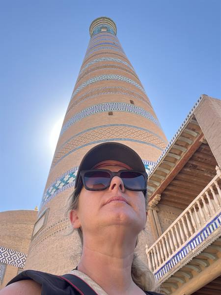 Turista con cappello e occhiali da sole davanti al minareto di Khiva
