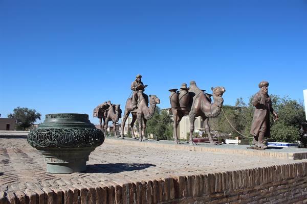 Statue bronze di cammelli e mercanti lungo il muro di mattoni, Bukhara