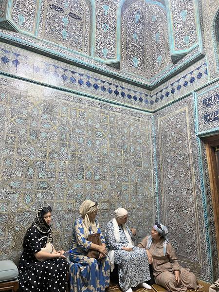 Donne velate sedute tra maioliche turchesi e blu, mausoleo di Shah-i-Zinda, Samarcanda