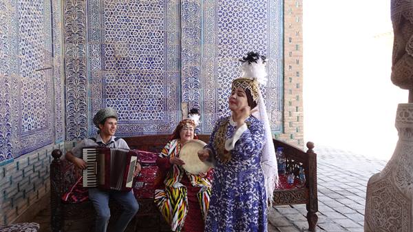 Musicisti in costume accanto a maioliche blu di Khiva