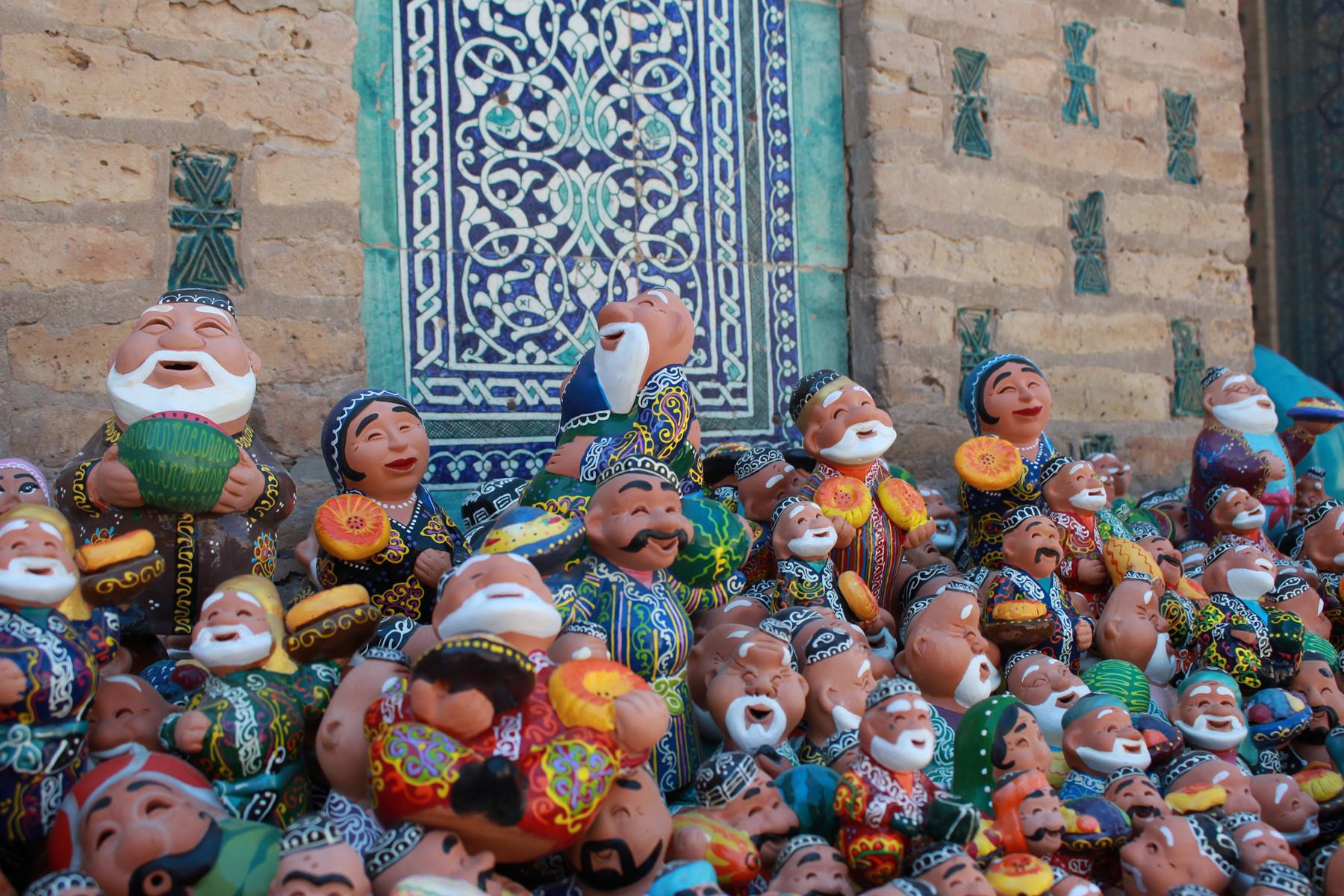 Statuine di ceramica colorate davanti a un mosaico di maioliche blu, Khiva