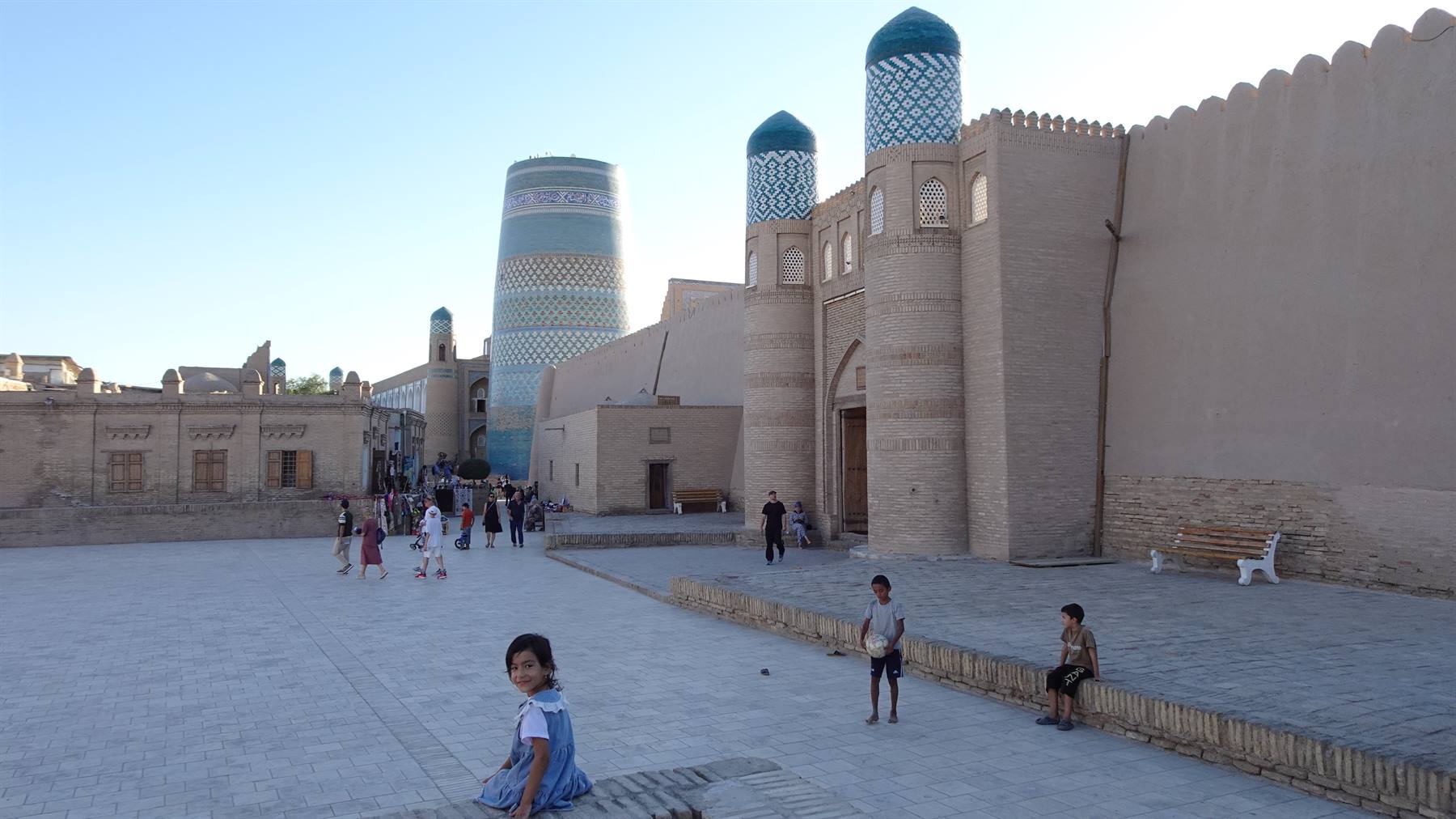 Bambini giocano in piazza davanti al minareto di mattonelle verdi, Khiva