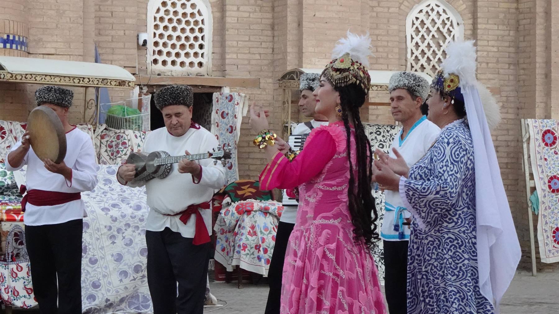 Musicisti e ballerine in costi tradizionali suonano davanti alle mura di Khiva