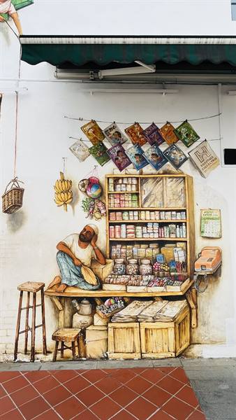 Mural on white wall: seated vendor in front of jars and goods stall