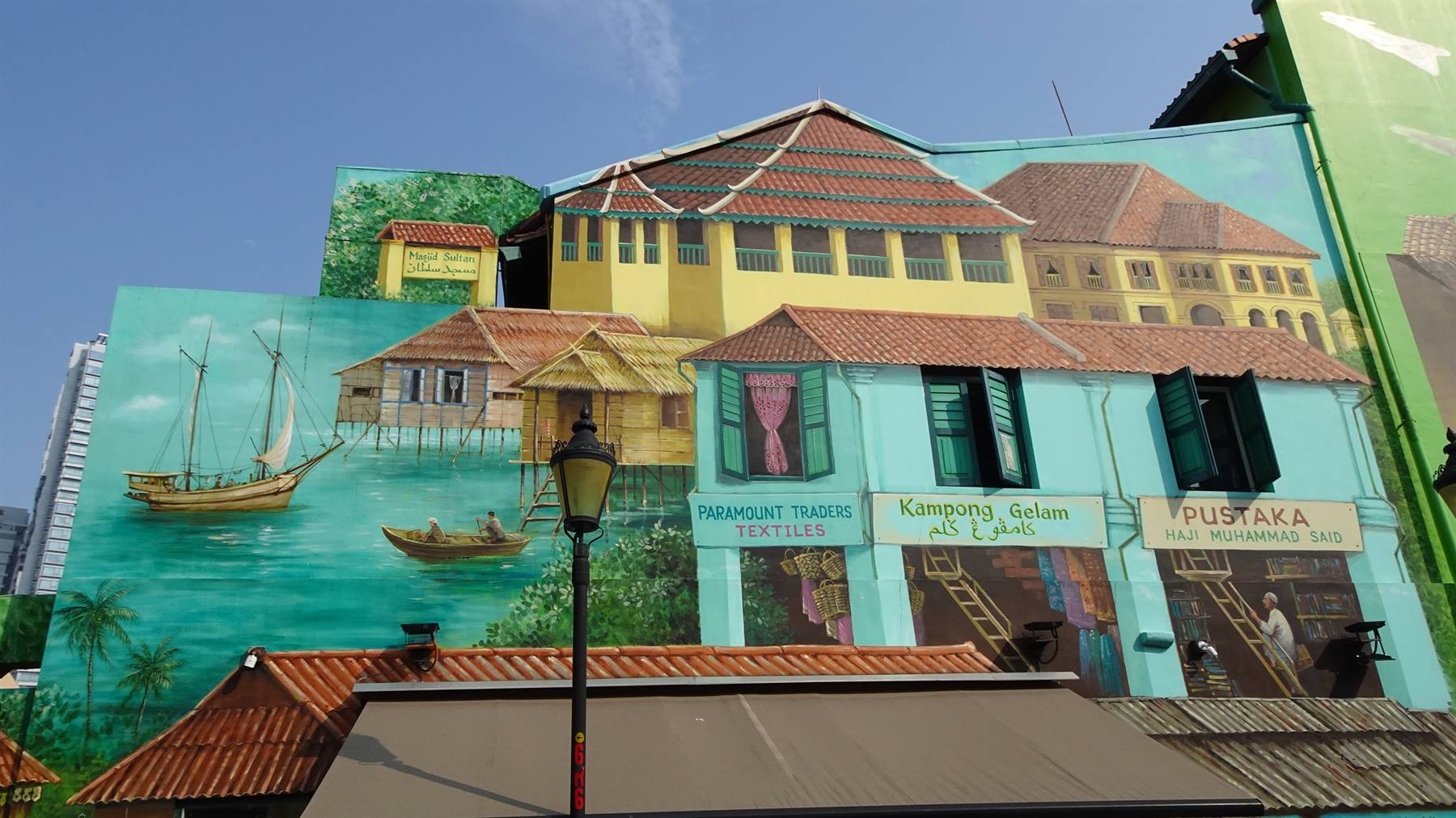 Murale dipinto su facciata con case tradizionali, barche a vela e insegne Kampong Gelam