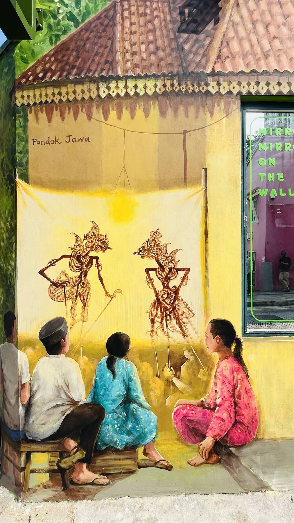 Murale di wayang kulit: spettacolo di ombre giavanese con spettatori seduti