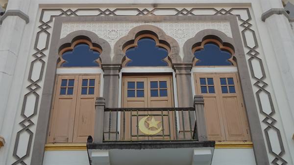 White facade with three Moorish doors, balcony and golden crescent moon emblem