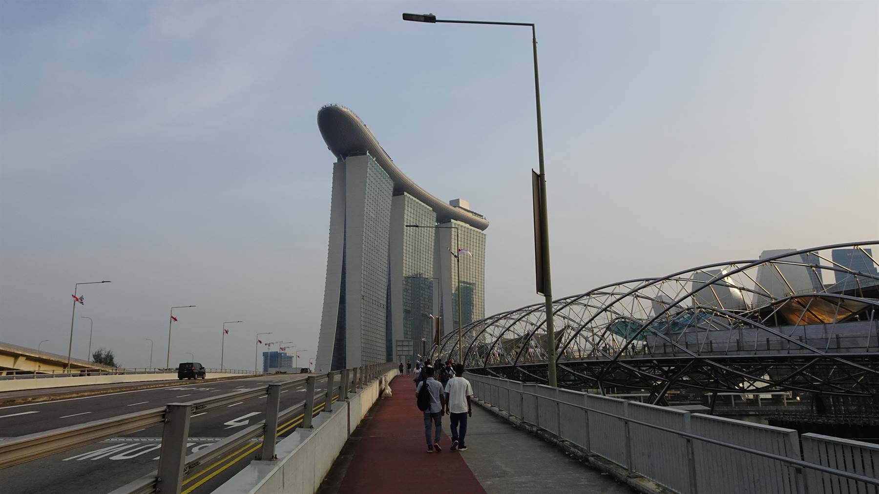 Turisti camminano sull'Helix Bridge verso il Marina Bay Sands a Singapore