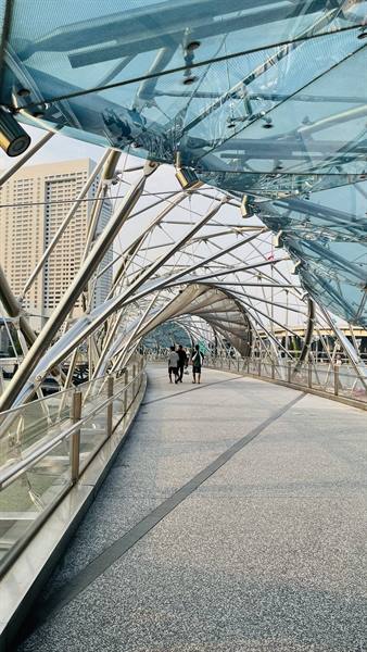 Pedestrians walk along Singapore's Helix Bridge amid steel and glass structures