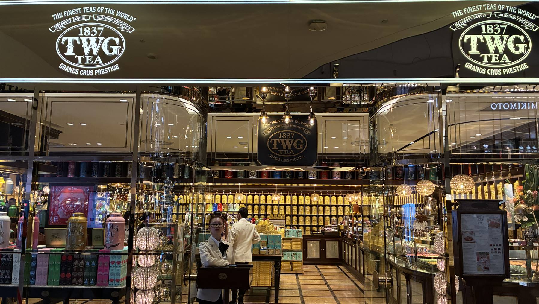 Boutique TWG Tea in centro commerciale, scaffali di scatole dorate, commessa alla cassa