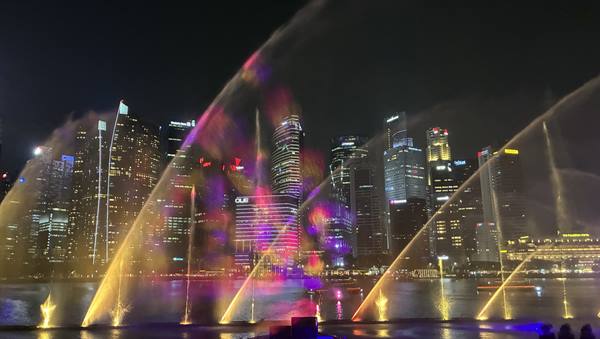 Illuminated fountains dancing on the bay before Marina Bay's skyscrapers
