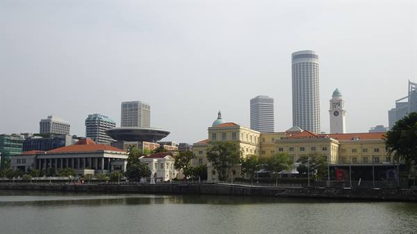 Under a veiled sky, Singapore mirrors calmly in the river waters.