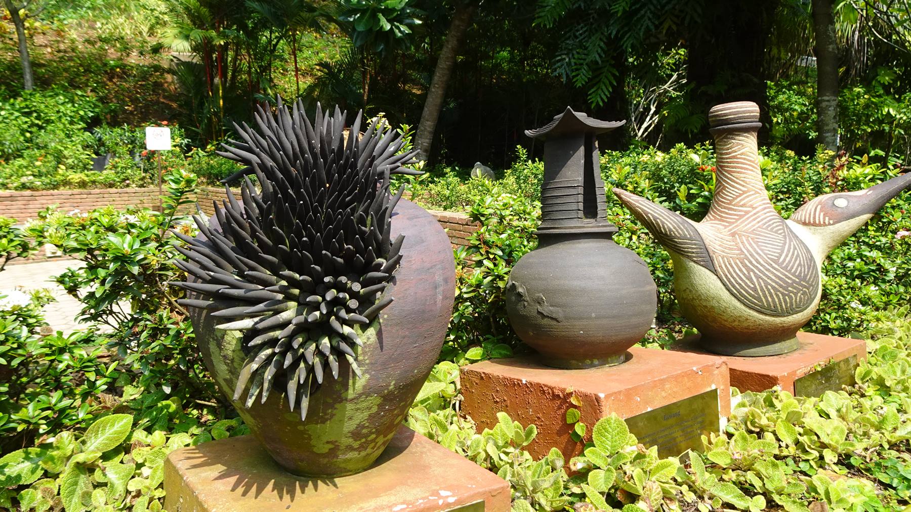 Sculture in ceramica su basi di mattoni in un giardino tropicale verde